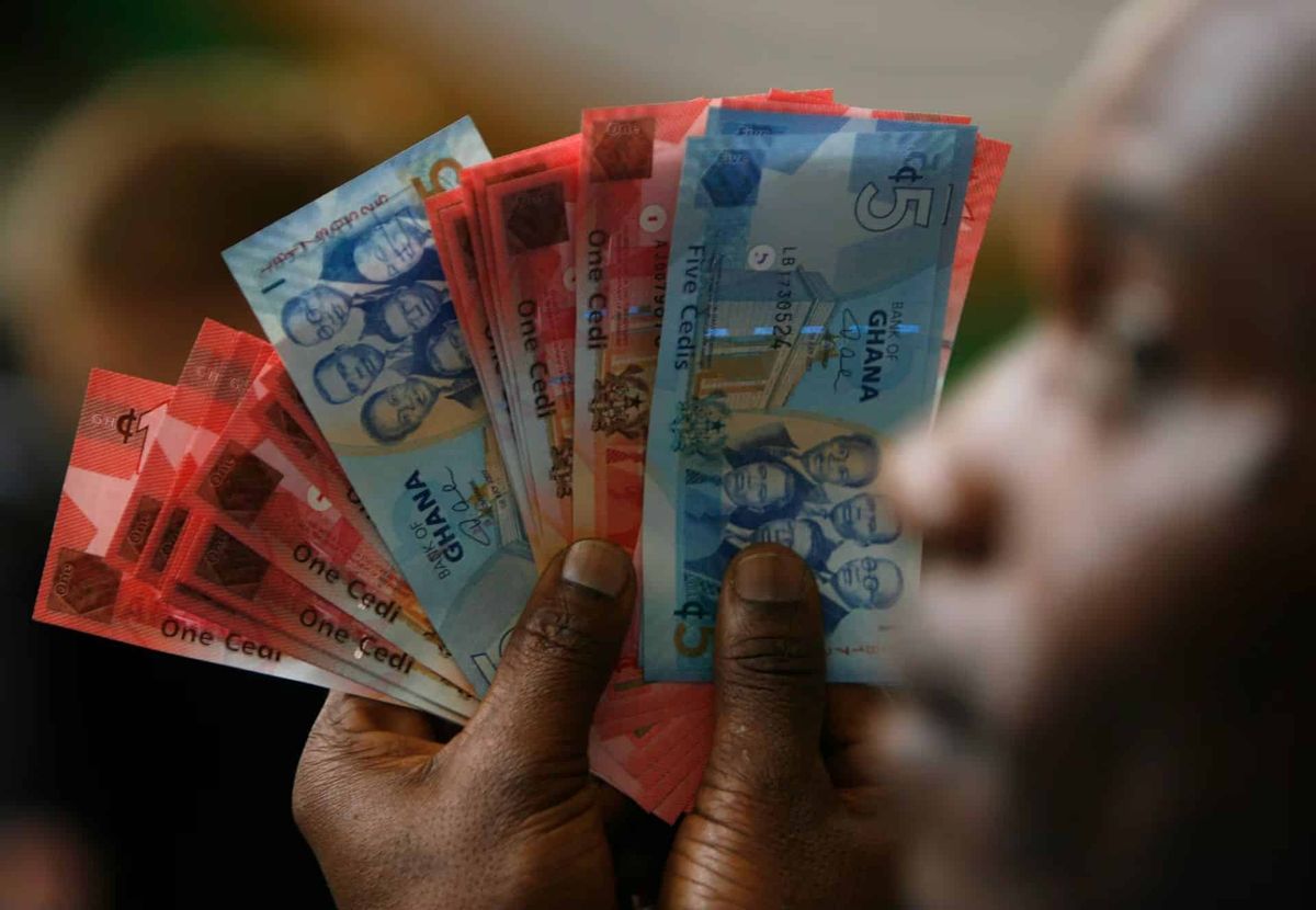 Bir adam Gana'nın sedi banknotlarını tutuyor.