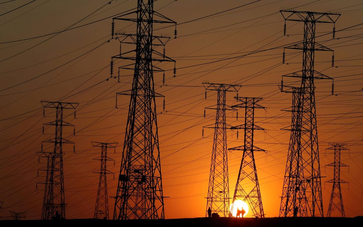 Güney Afrika'da Orlando, Soweto'da yerel halk işten dönerken elektrik direklerinin yanından geçiyor.