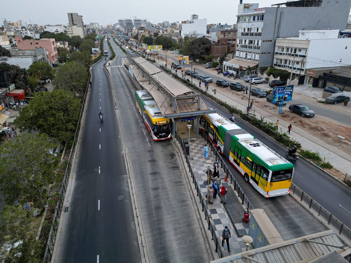 Dakar BRT elektrikli otobüsleri yanında duran insanlar