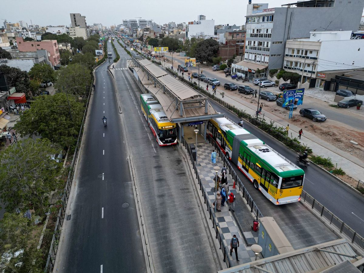 Dakar BRT elektrikli otobüsleri yanında duran insanlar